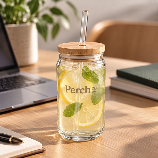 Perch Co branded glass can tumbler with a bamboo lid and glass straw, filled with iced lemon water