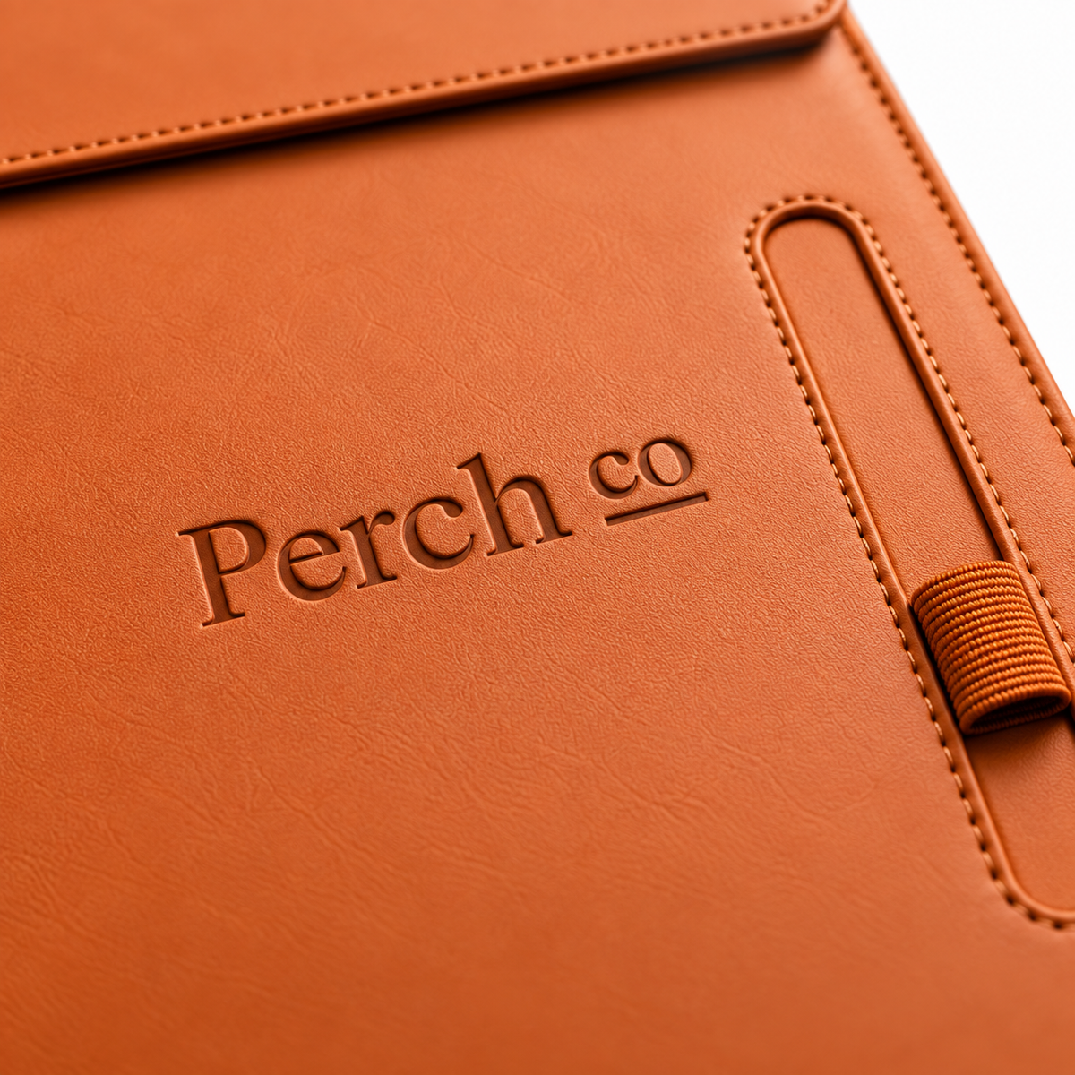 Close-up of a debossed logo, stitched edge and pen loop on an orange A4 folder