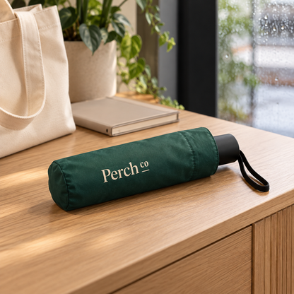 Folded compact umbrella on a desk beside a tote bag on a rainy day