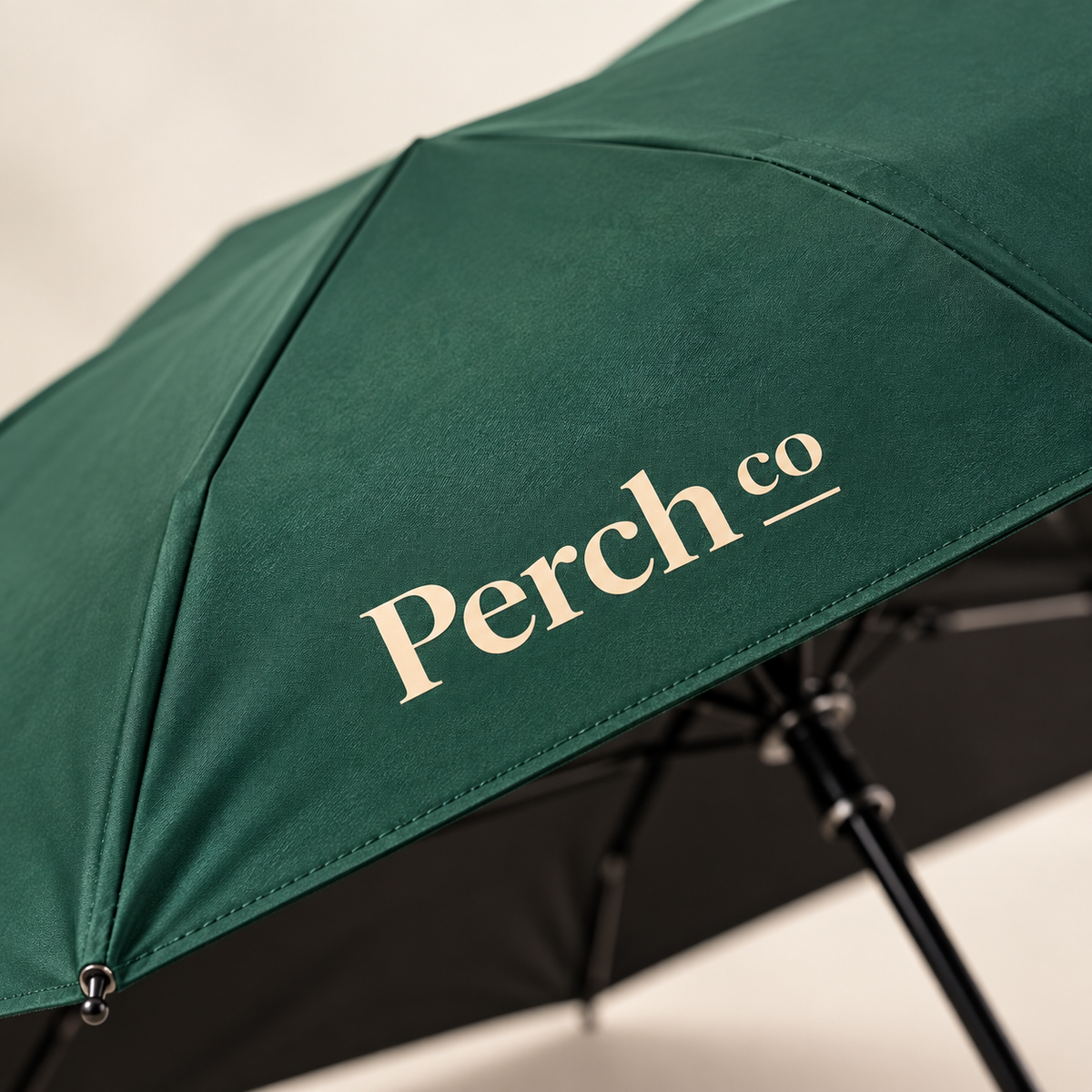 Close-up of the printed logo on the green canopy of the wooden-handle umbrella