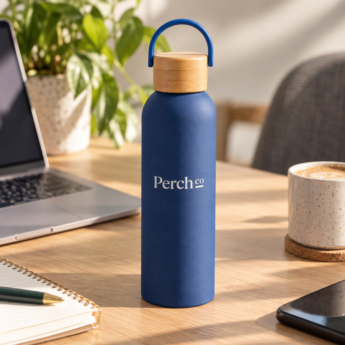 Branded bamboo lid water bottle on a desk beside a laptop, notebook and coffee