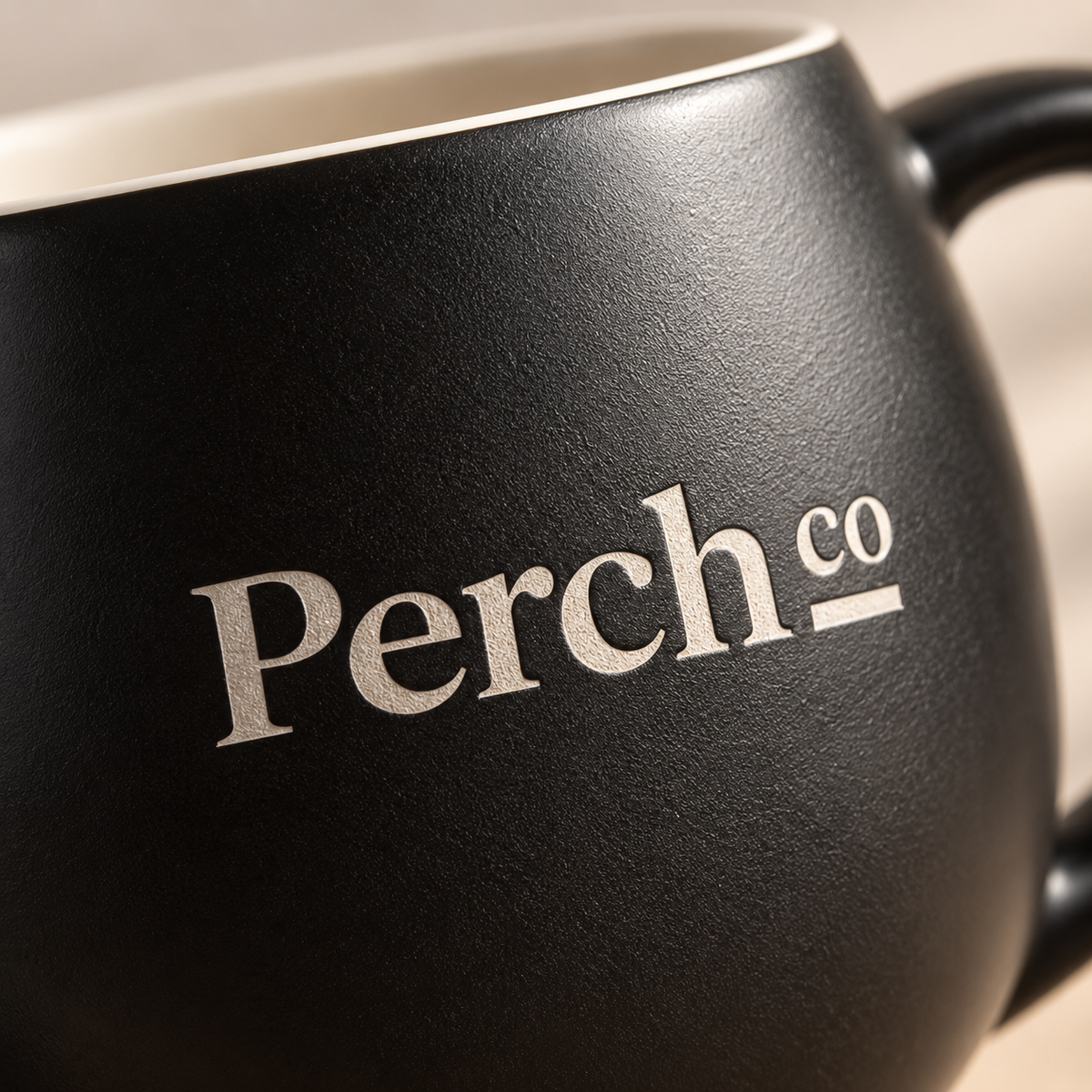 Close-up of the Perch Co logo printed on a matte black ceramic bulb mug