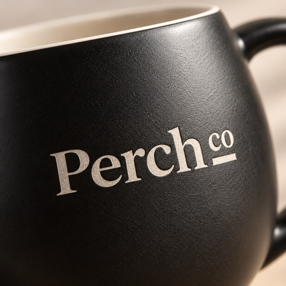 Close-up of the Perch Co logo printed on a matte black ceramic bulb mug