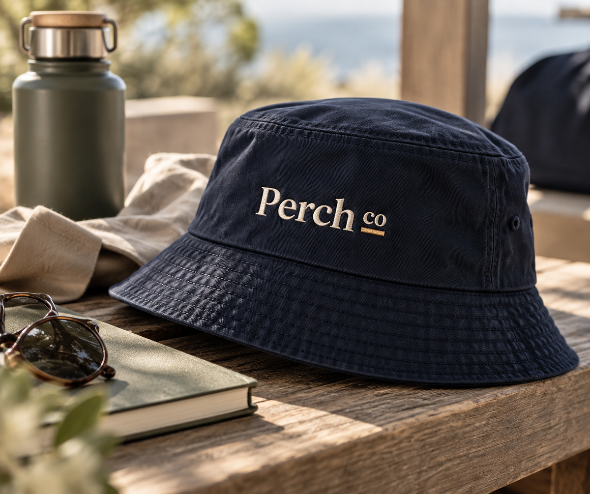 Detail of the embroidered logo and topstitched brim on the navy bucket hat