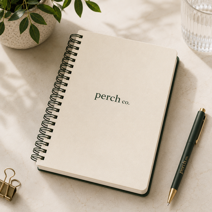 Cream spiral notebook with printed logo beside a pen