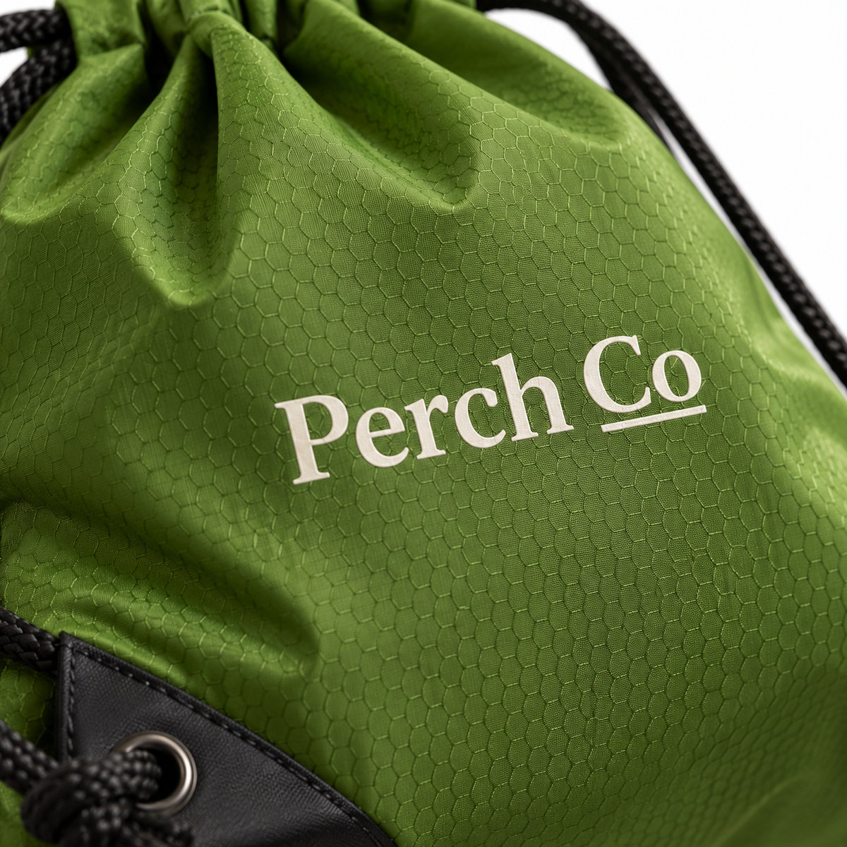 Close-up of the printed logo and reinforced corner eyelet on the drawstring bag
